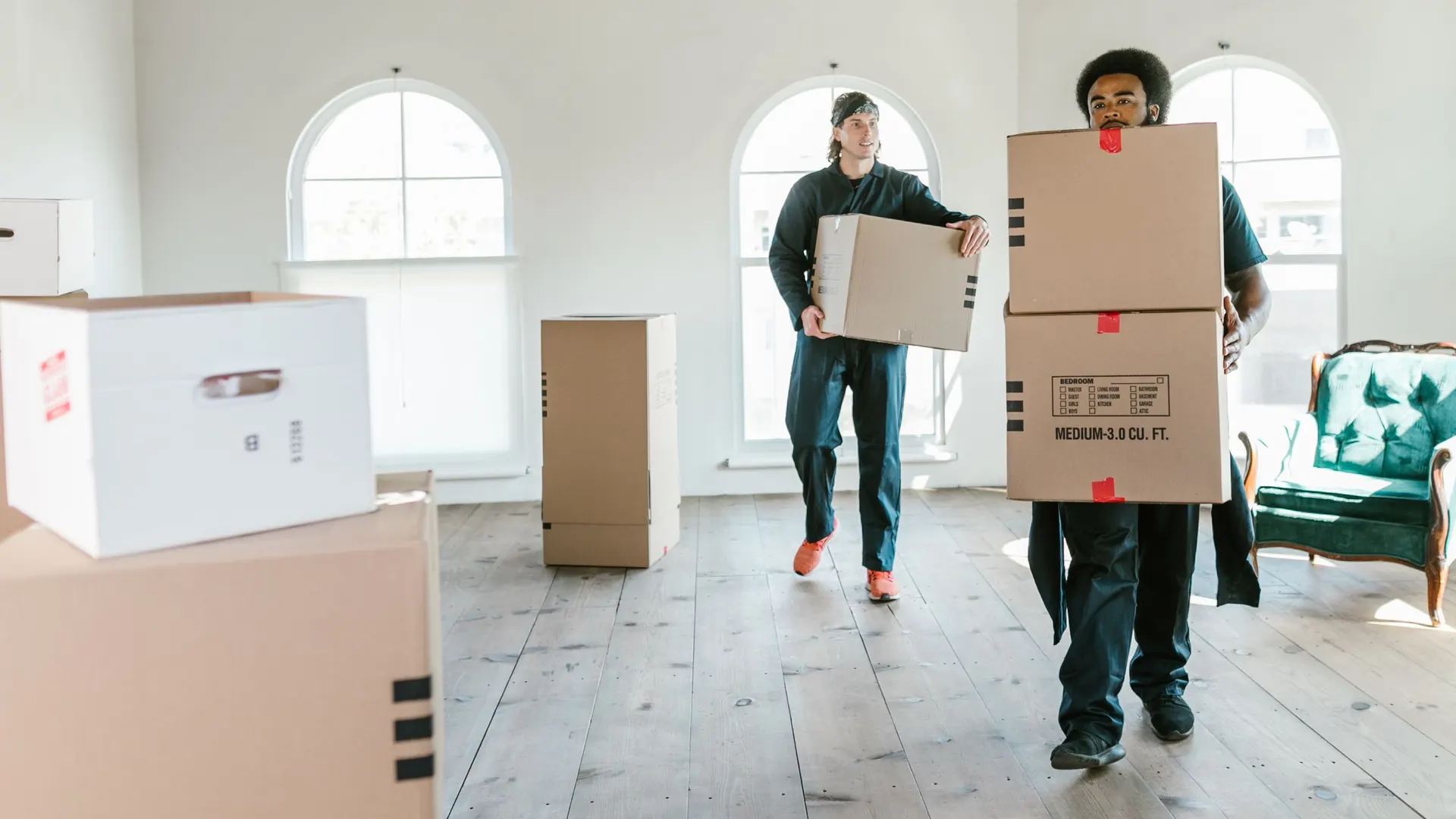 Two crew members carrying boxes out of a home